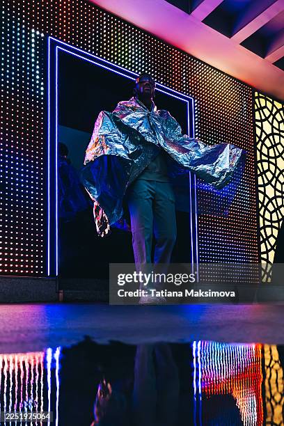 a futuristic portrait of an african american man wearing reflective visor sunglasses and wrapped in a metallic cloak. - vanguardista imagens e fotografias de stock