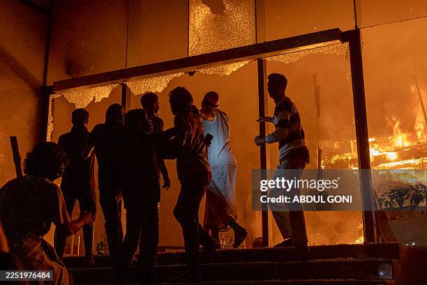 People are seen at the entrance to the Daily Star building as it burns in Dhaka on December 19 amid protests following the news of the death of youth...