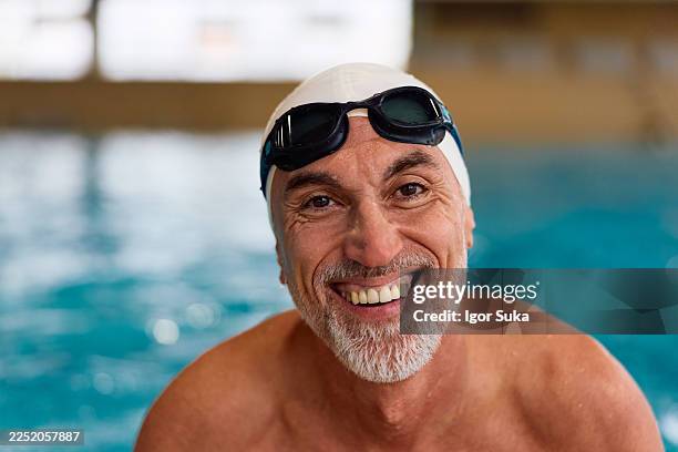 senior man smiling wearing swim cap goggles pool - swimming cap stock pictures, royalty-free photos & images