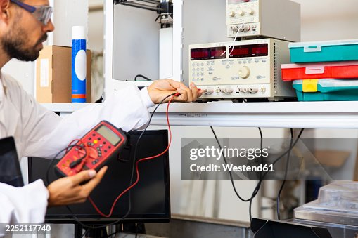 Lab technician testing electronics with voltage meter in innovation lab Lab technician testing electronics with voltage meter in innovation lab