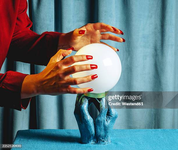 woman in red using a crystal ball for fortune telling indoors - crystal ball stock pictures, royalty-free photos & images