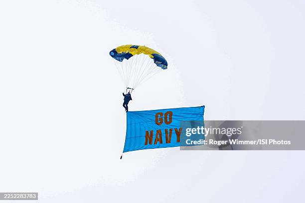 Navy Seal parachutes into the stadium with a go navy flag before a game between the Navy Midshipmen and Army West Point Black Knights at M&T Bank...