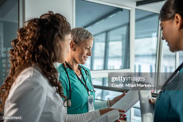 healthcare professionals collaborating on patient charts, discussing medical records - medical staffing solutions stock pictures, royalty-free photos & images