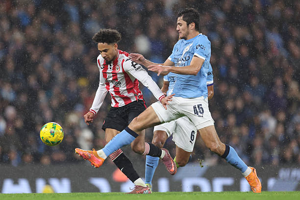 Kevin Schade of Brentford is fouled by Abdukodir Khusanov of Manchester City resulting in a yellow card during the Carabao Cup Quarter Final match...