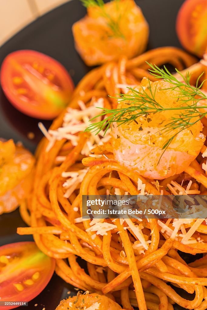 Close-up of delicious shrimp pasta with tomatoes and cheese on a black plate, ready to eat