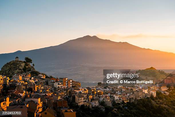 sicilian hillside village at sunset with mount etna in the distance, centuripe, sicily - etna foto e immagini stock