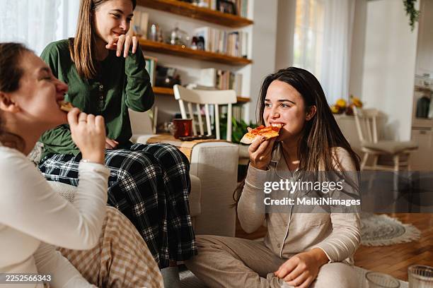 los amigos disfrutan de una noche de pizza en casa durante una reunión acogedora en interiores, con conversación y risas - comida salada fotografías e imágenes de stock