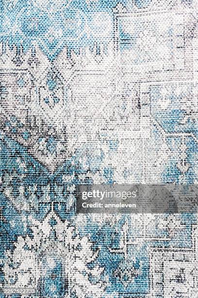 Distressed carpet texture with an oriental pattern in blue, white, and gray creating an abstract grunge background
