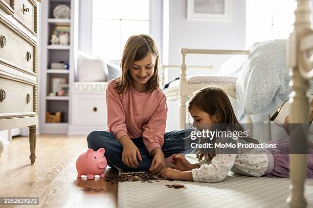 young sisters counting change next to piggy bank - counting stock pictures, royalty-free photos & images