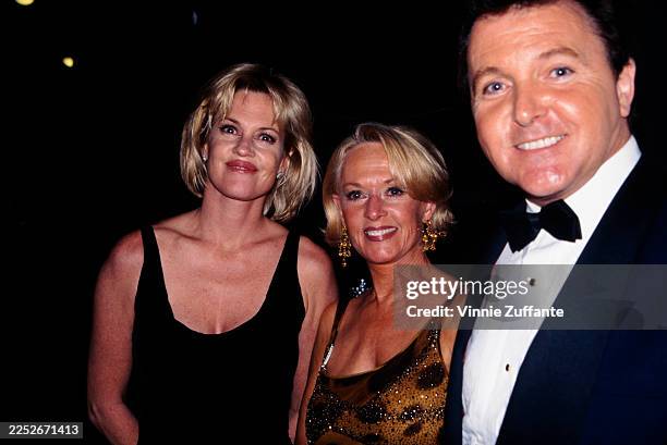 American actress Melanie Griffith, wearing a sleeveless black scoop-neck outfit, with her mother, American actress Tippi Hedren, who wears a...