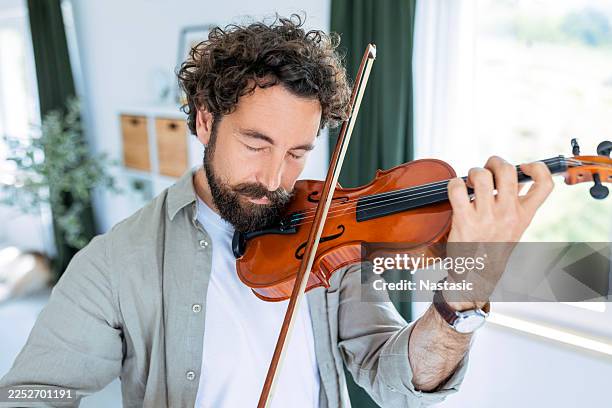 violinist practicing music at home with natural light - classical musician stock pictures, royalty-free photos & images