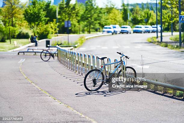 bicycle parked in urban park bike rack on sunny day - vitoria stock-fotos und bilder