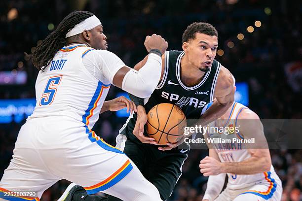 Victor Wembanyama of the San Antonio Spurs drives to the basket around Luguentz Dort of the Oklahoma City Thunder during the second half at Paycom...