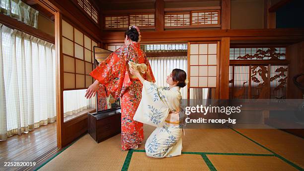 une femme s’habille en kimono par un professionnel - kimono photos et images de collection