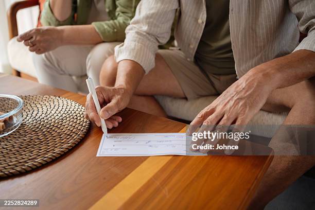 man writing check for a financial payment or bill - check bildbanksfoton och bilder