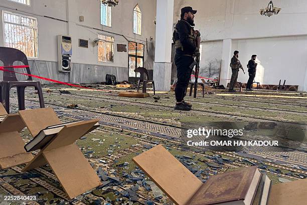 Armed men stand inside the Imam Ali ibn Abi Talib Mosque following an explosion in the Wadi al-Dahab neighborhood of Homs on December 26, 2025. A...