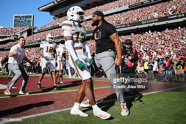 Bryce Fitzgerald of the Miami Hurricanes celebrates with safeties coach Will Harris after intercepting a pass in the fourth quarter against the Texas...