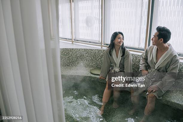 asian couple relaxing relaxing in a steamy spa bath wearing bathrobes, kuala lumpur - balneotherapy stock pictures, royalty-free photos & images