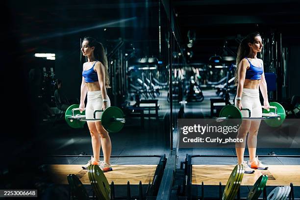 a determined young woman performs deadlifts with a trapezoid barbell in a modern gym. concept of strength, discipline, and determination. - deadlift stock pictures, royalty-free photos & images