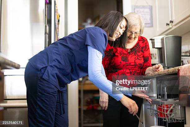 a home health aid nurse helping a senior woman around the house. - chores stock pictures, royalty-free photos & images