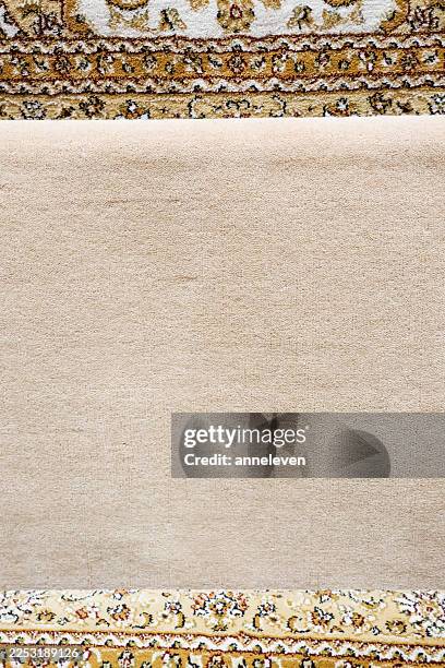 Rolled up beige rug showing soft fabric texture with traditional oriental floral pattern border design
