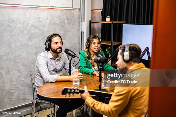 podcast hosts looking singer playing a guitar on a studio - radio show stock pictures, royalty-free photos & images