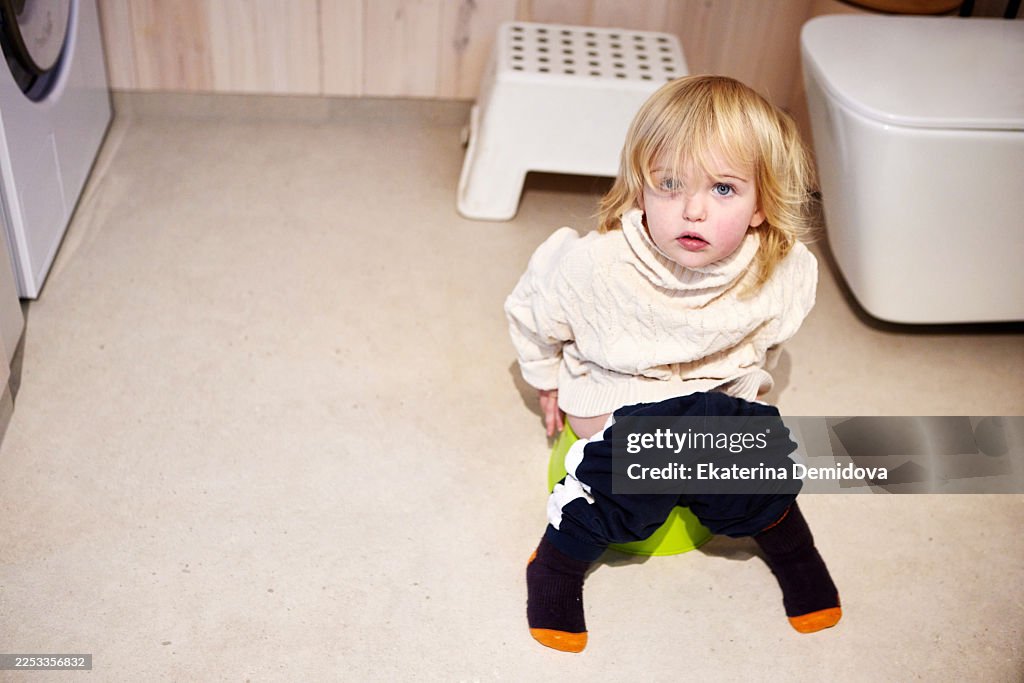 Toddler boy learning potty training in bathroom