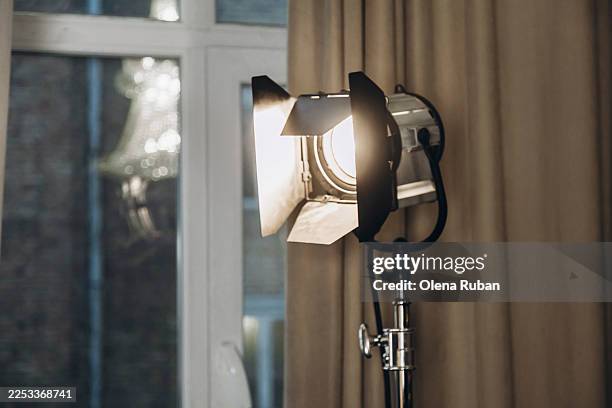 a studio light with barn doors sit by a window with a beige curtain. - tripod stock pictures, royalty-free photos & images