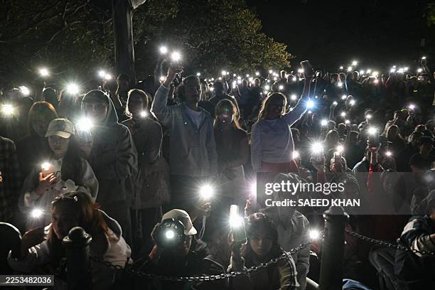 People turn on their mobile phones' flashlights as they observe a minute's silence to reflect on the tragic Bondi Beach shooting attack before New...