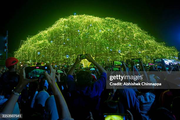 People take photos of an illuminated tree in a park on Christmas Day on December 25, 2025 in Kochi, India. Christian faithful are observing the...