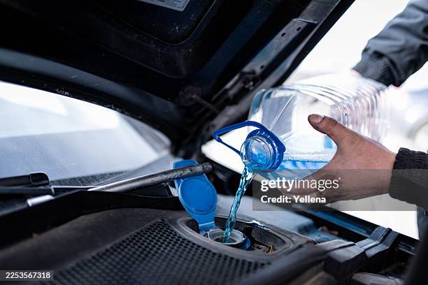 primer plano de un hombre comprobando y aplicando anticongelante al coche - arandela fotografías e imágenes de stock