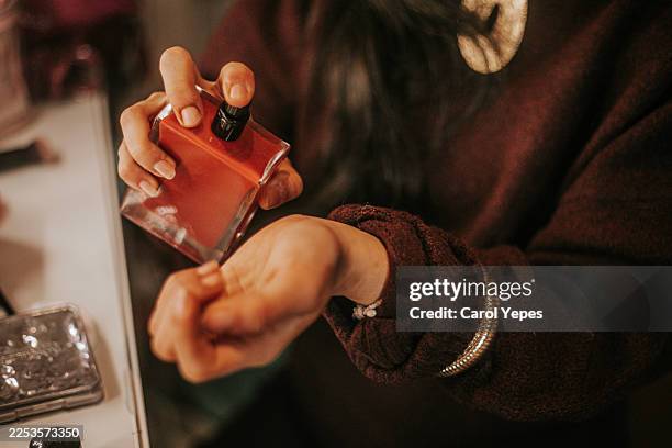woman applying perfume to her wrist, capturing a delicate and intimate moment associated with personal care, beauty routines, - profumo foto e immagini stock