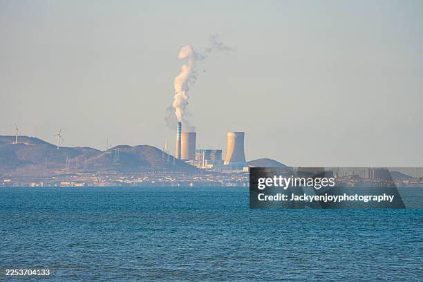 white smoke is coming from the nuclear power plant's massive cooling tower. this is the beachfront power plant. - fumée pollution de lair photos et images de collection
