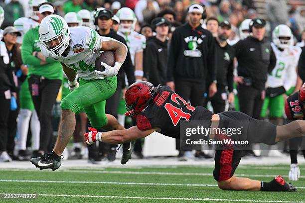 Running back Caleb Hawkins of the North Texas Mean Green escapes a tackle attempt from linebacker Brady Anderson of the San Diego State Aztecs during...