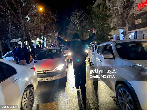 Protester flashes victory signs as traffic slows during demonstrations in Hamedan, Iran on January 1, 2026. The demonstrations erupted after...