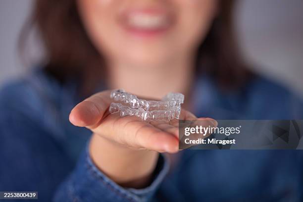 woman holding clear aligners for teeth straightening modern invisible orthodontic treatment. - aparelho dentário imagens e fotografias de stock