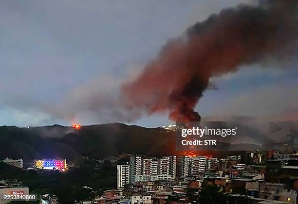 Fire at Fuerte Tiuna, Venezuela's largest military complex, is seen from a distance after a series of explosions in Caracas on January 3, 2026. The...