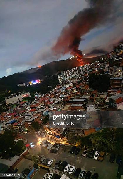 Fire at Fuerte Tiuna, Venezuela's largest military complex, is seen from a distance after a series of explosions in Caracas on January 3, 2026. The...