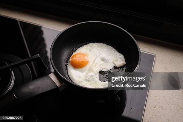 fried egg cooking in a small pan on the gas stove - fried egg stock pictures, royalty-free photos & images