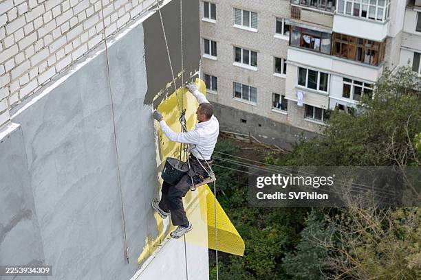 el trabajador de construcción está colocando mallas de refuerzo sobre la superficie de paneles de poliestireno en la novena planta de un edificio. - recubrimiento capa exterior fotografías e imágenes de stock