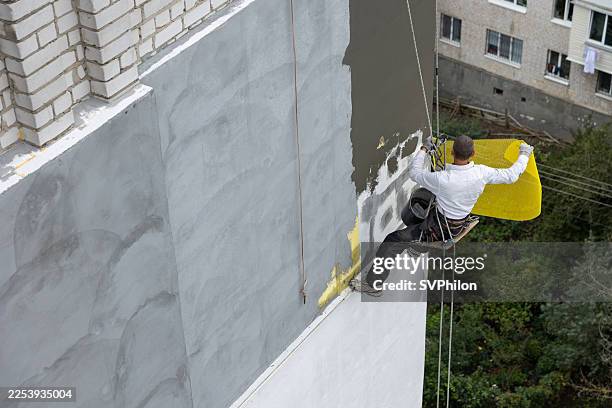 el trabajador de construcción está colocando mallas de refuerzo sobre la superficie de paneles de poliestireno en la novena planta de un edificio. - recubrimiento capa exterior fotografías e imágenes de stock