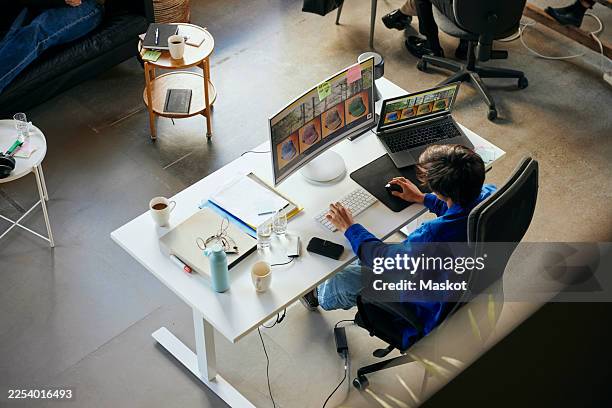 high angle view of male programmer working on desktop pc in tech startup office - desk angle stock pictures, royalty-free photos & images