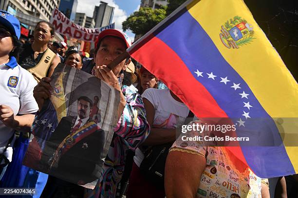 Pro-government demonstrator holds a banner with a picture of Nicolas Maduro and the Venezuelan flag during a rally a day after the capture of Nicolas...