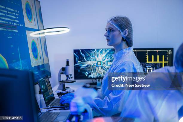 professional technician in sterile coverall inspecting a colorful reflective semiconductor wafer with gloves inside a cleanroom at a semiconductor manufacturing plant, representing advanced microchip technology and quality control. - computer cookies stock pictures, royalty-free photos & images