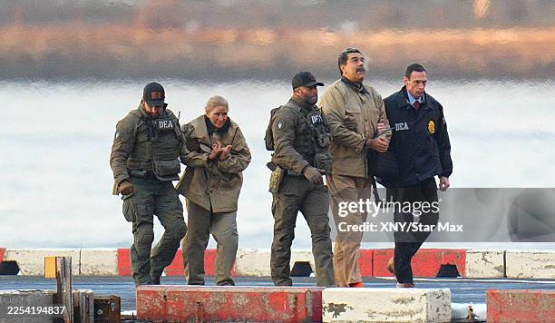 Nicolas Maduro and his wife, Cilia Flores, are seen in handcuffs after landing at a Manhattan helipad, escorted by heavily armed Federal agents as...