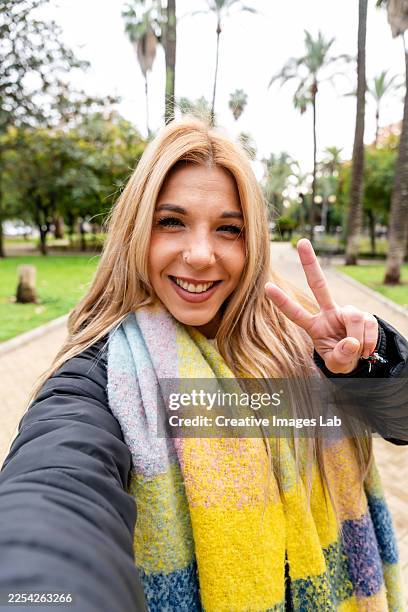 young adult woman taking selfie making peace sign - sjaal stockfoto's en -beelden