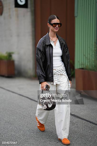 Jacqueline Zelwis is seen wearing a black oversized leather jacket with relaxed dropped shoulders and a pointed collar; a fitted white ribbed knit...