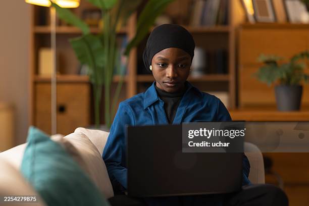 jeune adulte noire travaillant sur un ordinateur portable à la maison - voile religieux photos et images de collection
