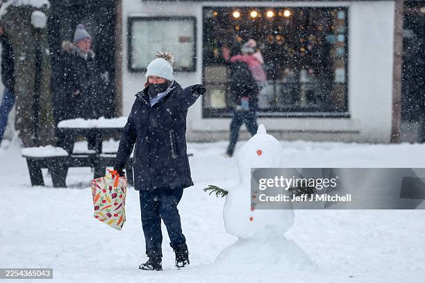 People walk through a snow shower as an 'amber' snow warning is issued on January 02, 2026 in Ballater, Scotland. Severe conditions were forecast in...