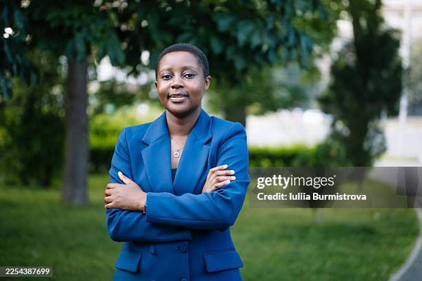 confident young woman in a blue blazer poses outdoors for a professional portrait in a park setting - initiative photos et images de collection